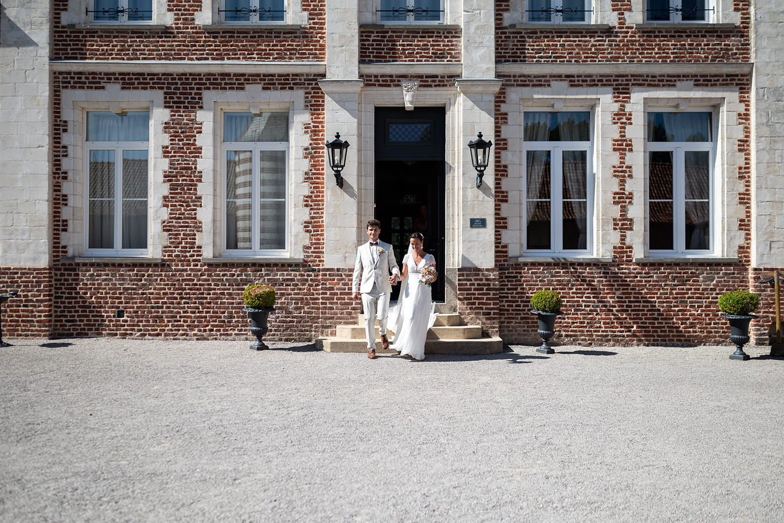Mariés devant la façade de la salle de mariage du Domaine de la Traxène