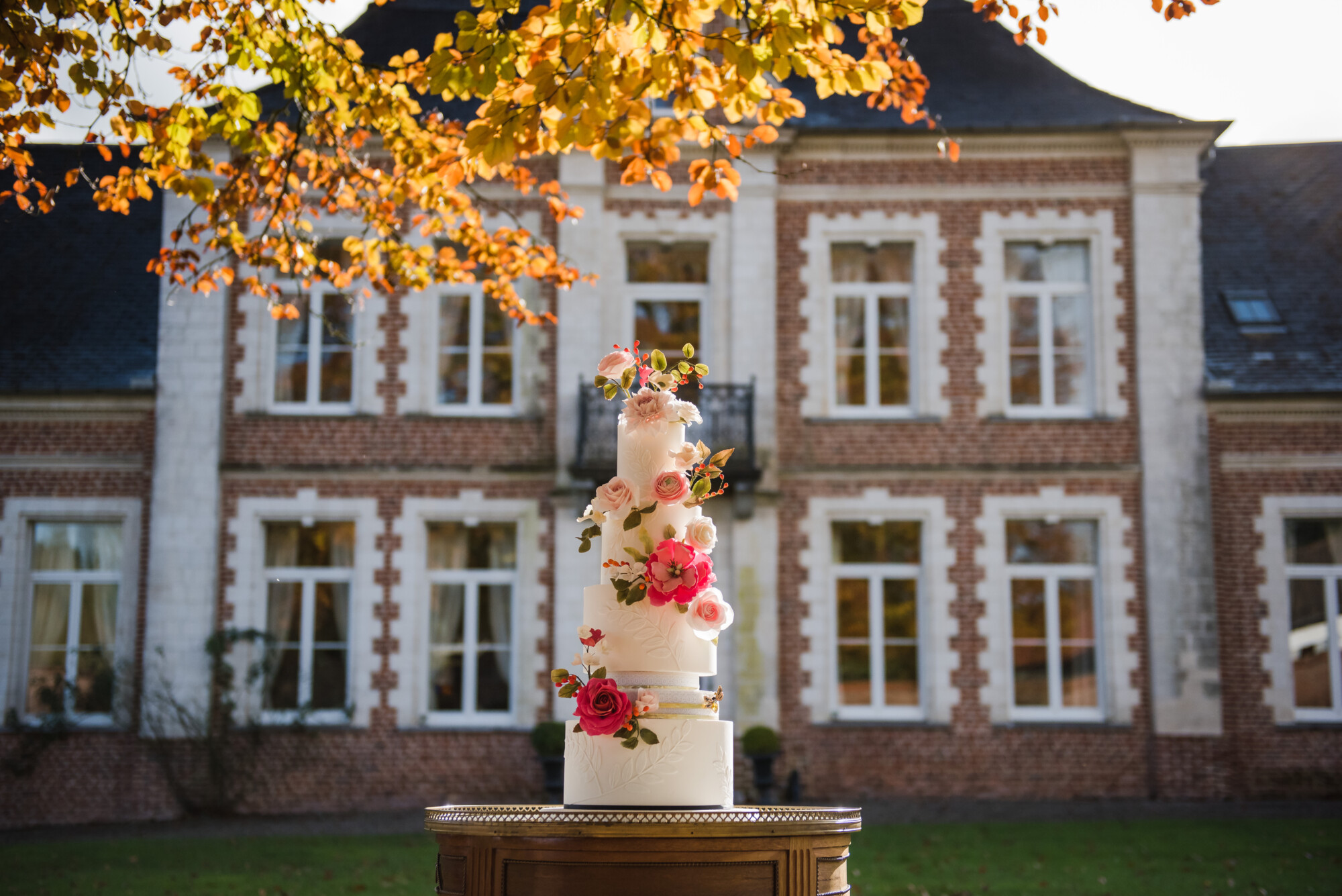 Wedding cake fleuri par notre traiteur partenaire Culin'R devant la façade du Domaine de la Traxène en automne