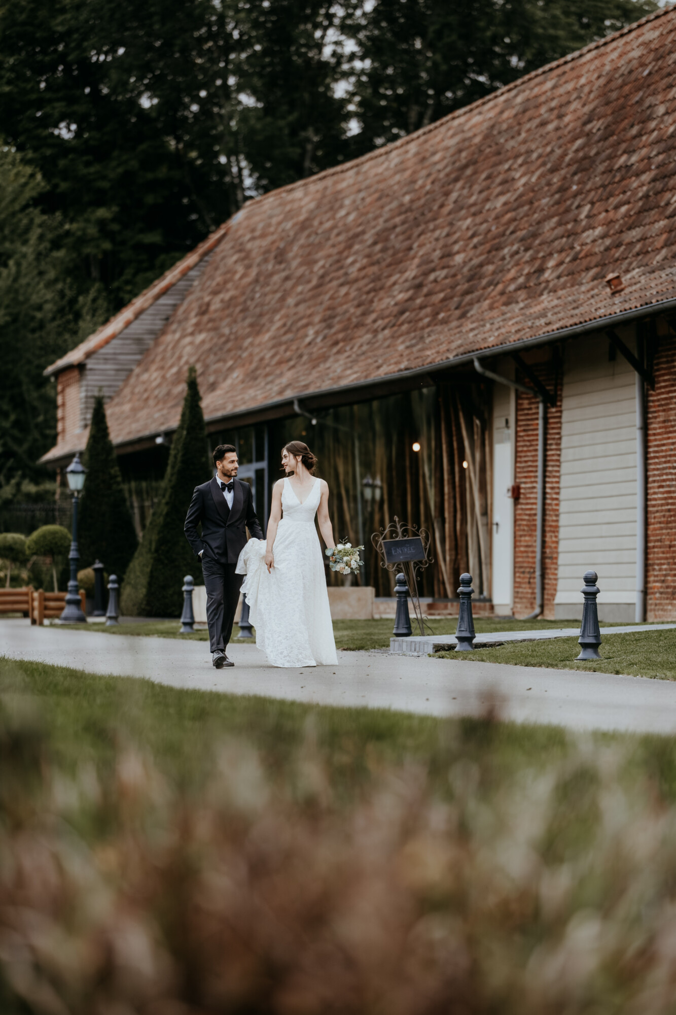 Couple de mariés se promenant devant la salle de réception du Domaine de la Traxène.