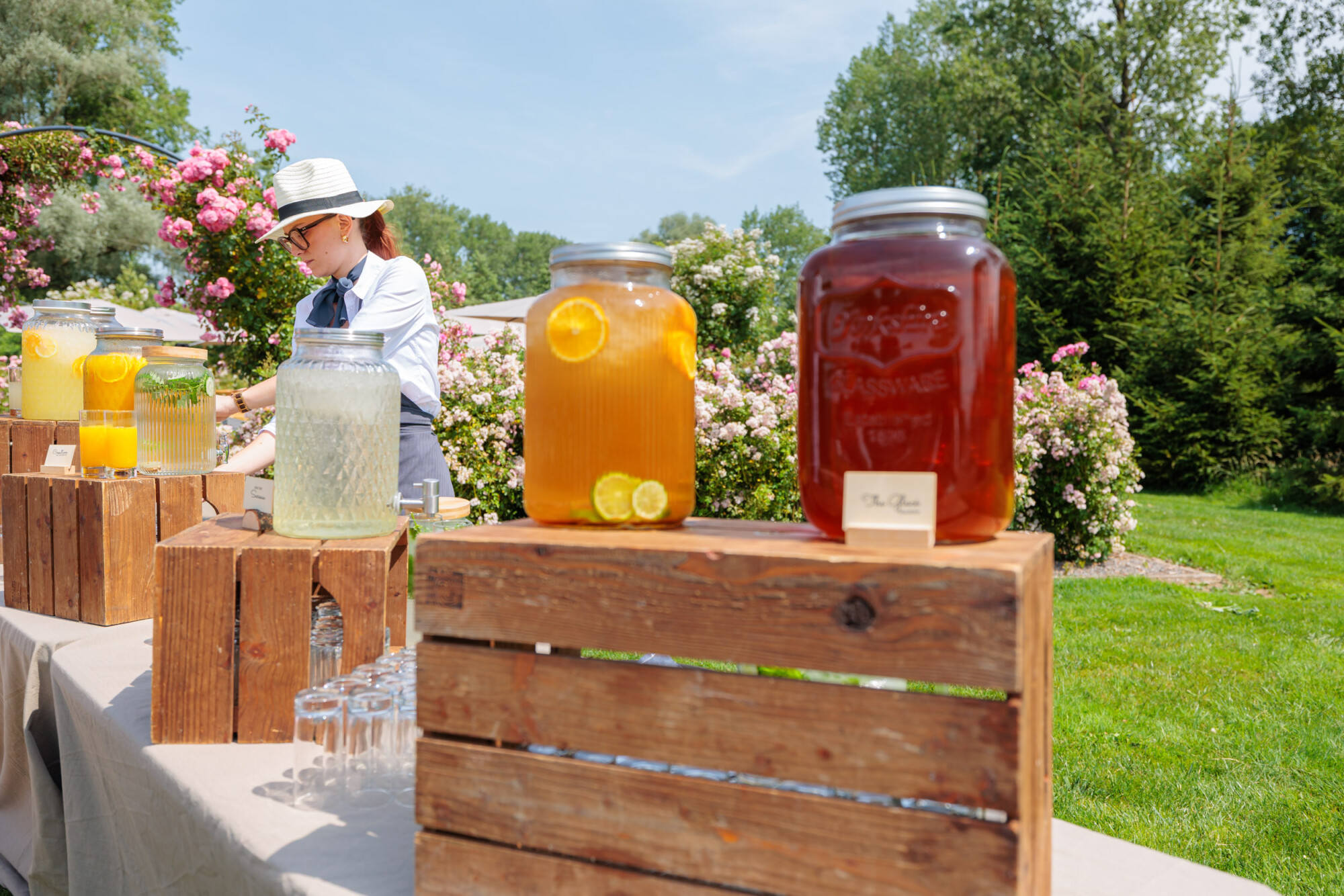 Prestataire de mariage préparant un bar à boissons fraîches dans la roseraie du Domaine de la Traxène.