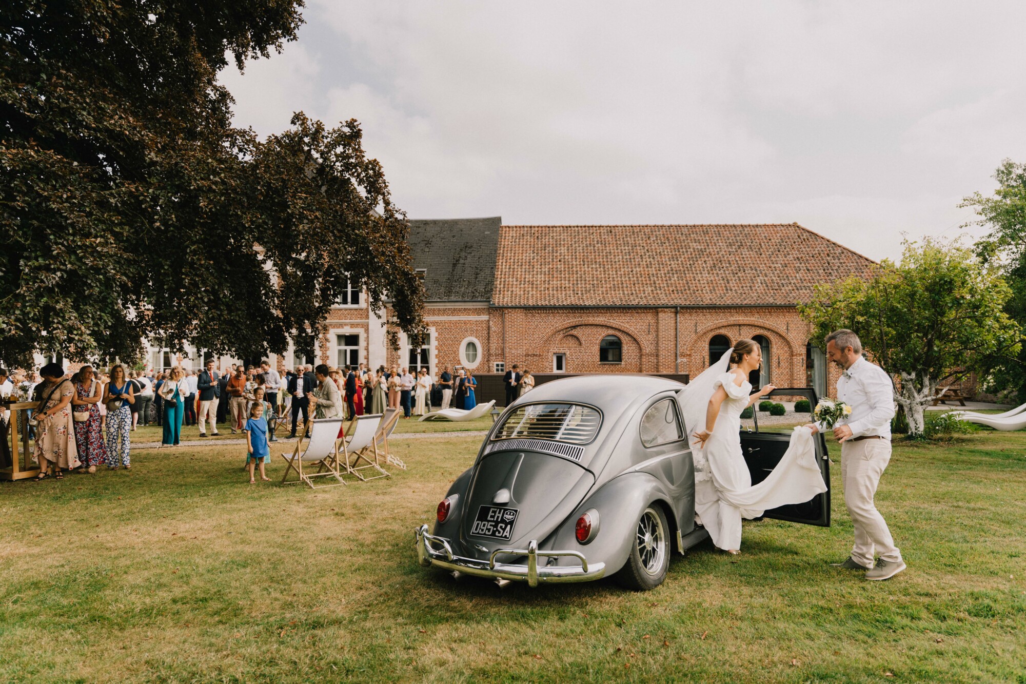 Arrivée de la mariée en voiture ancienne dans les jardins du Domaine de la Traxène.