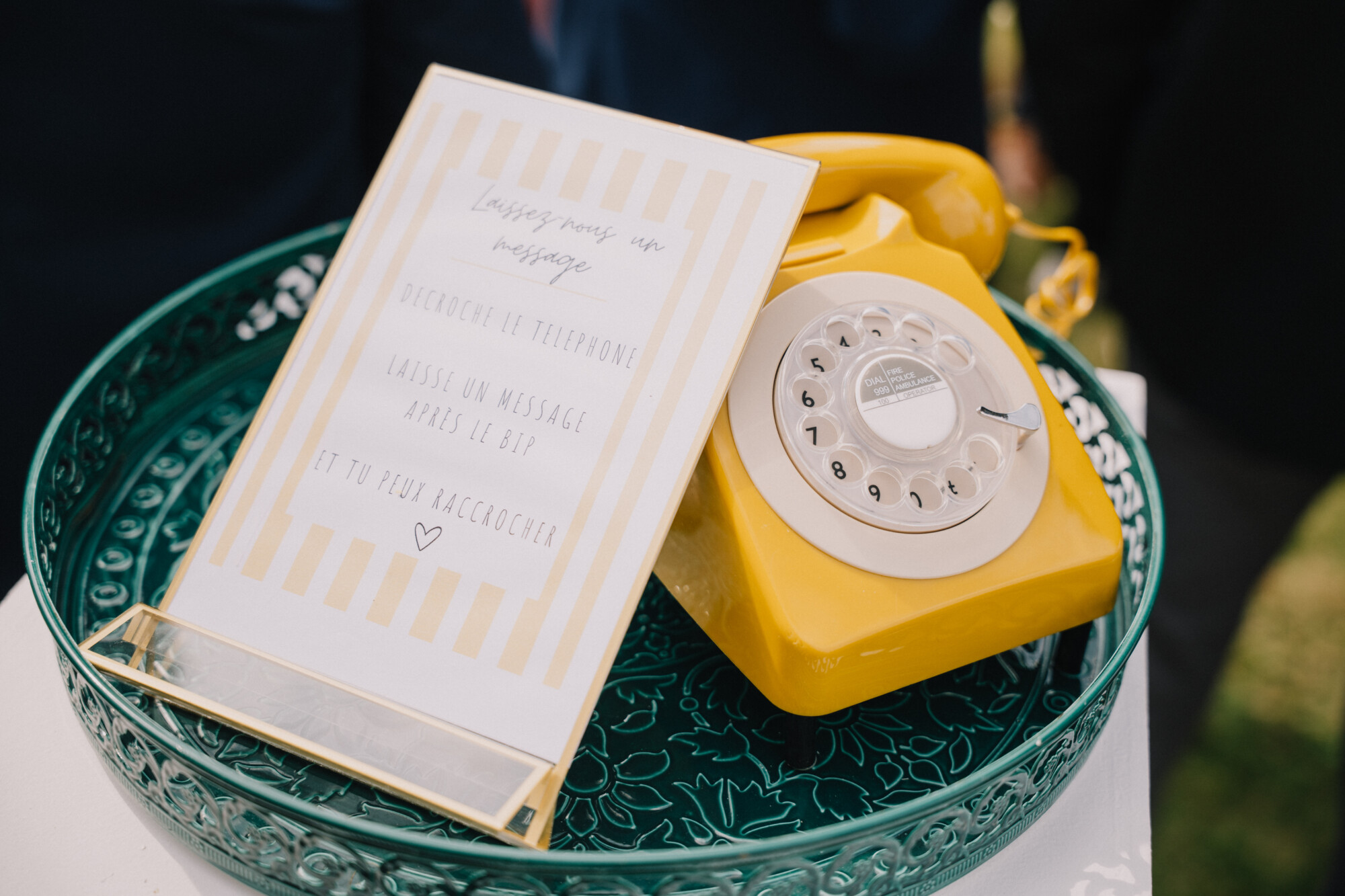 Téléphone vintage jaune accompagné d’un livret posé sur une table décorative, une animation originale pour recueillir les messages des invités lors d’un mariage.